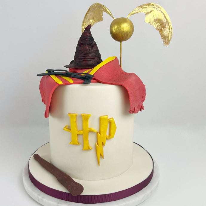 Hand-sculpted Golden Snitch wizard theme cake with wafer wings, sorting hat and wand